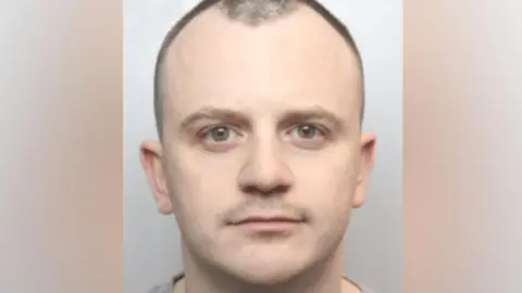 Greater Manchester Police PC Dean Dempster with brownish  eyes and receding achromatic  hairsbreadth  looking impassively 