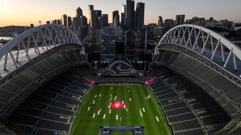 Getty Images A picture of one of the FIFA World Cup stadiums. The stadium has thousands of seats and a city in the background. 