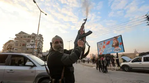 AFP Một chiến binh phiến quân Syria bắn chỉ thiên ở thành phố Hama, Syria (5 tháng 12 năm 2024)