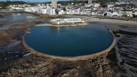 A general view of the lido. There is a large body of water with houses and buildings in the distance.