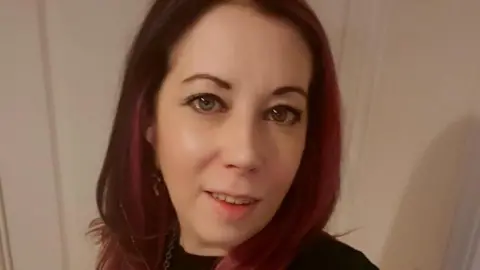 A photo of Amy Louise Stafford, who died after a house fire. She has long red hair and is pictured in a selfie, looking at the camera and smiling.
