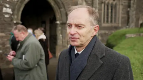 Justin Leigh stood to the right in front of the church at Craig Rich's funeral 