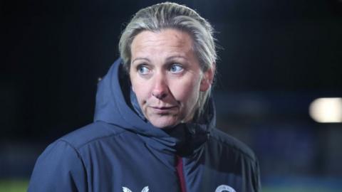 Carla Ward, wearing an Aston Villa jacket, looks on