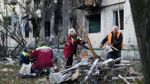 Reuters Work to clear the debris, outside the site of the damaged area during the combat drone and Russian attack, Russian attack in Wendur, in Kyiv
