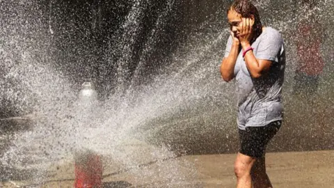 A woman cools off at a fire hydrant in the Manhattan borough of New York City