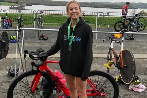 Zoe Tucker Zoe poses with the bike in a black hoodie at an event by the sea.