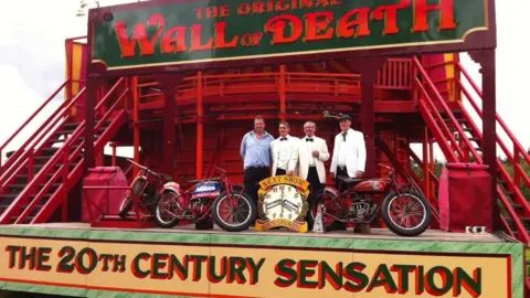 Family handout An image of James Messham alongside three other men stood on a stage which presents the "Wall of Death" motorcycles can be seen on the stage and a sign reading "The 20th Century Sensation"