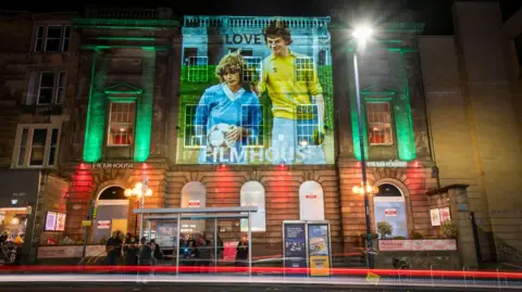 An image from the Scottish coming-of-age romantic comedy film Gregory’s Girl projected onto the Filmhouse in Edinburgh, is one of several classic movie images projected onto landmarks and public buildings in the city as part of the campaign to save the Edinburgh International Film Festival and the Filmhouse.