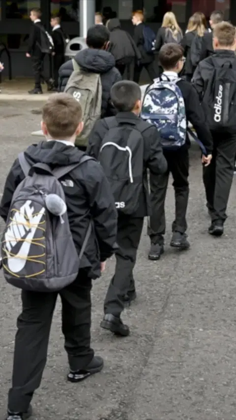 A line of children make their way into school