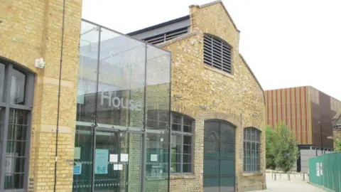 The entrance to Sand Martin House - a converted Victorian railway building. It is a light-coloured brick building with a big glass entranceway.