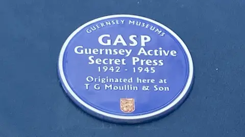 The blue plaque engraved with the words: GASP - Guernsey Active Secret Press 1942-1945. Originated here at T G Moullin & Son.