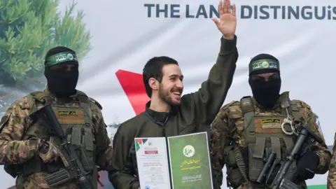 Omer Shem Tov is one of five hostages released by Hamas in Gaza. He can be seen waving as he is escorted on stage by Hamas militants