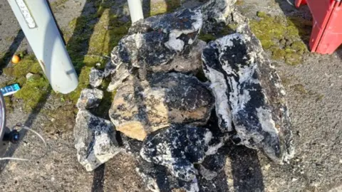 Thames Water Lumps of fatberg piled up at the side of a road - it looks like large boulders.