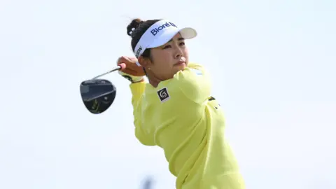 Miyu Yamashita wearing a yellow jumper and white trousers