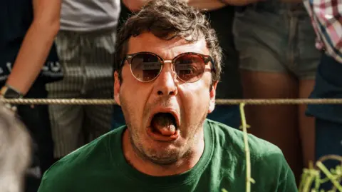 A contestant looks horrified and as if he might vomit while taking part in the nettle eating contest