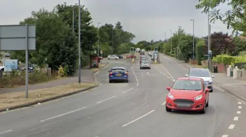 Google A general view of Derby Road. It is a two lane road with access to the Asda supermarket on the right.