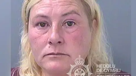 South Wales Police Rebekah Edwards mugshot. She has shoulder length blonde hair and is wearing a red top.