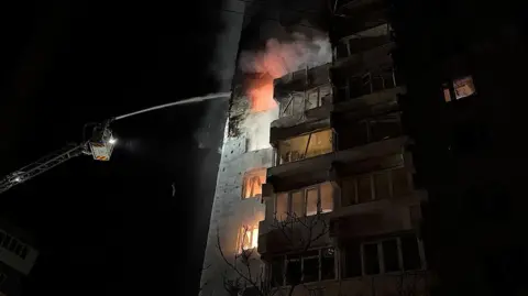 Getty Images Firefighters extinguish a fire in an apartment building following a Russian air attack in Zaporizhzhia