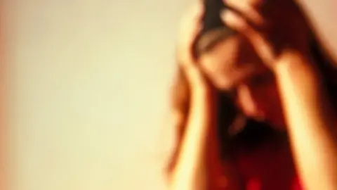 Science Photo Library Upset woman holding her head in her hands