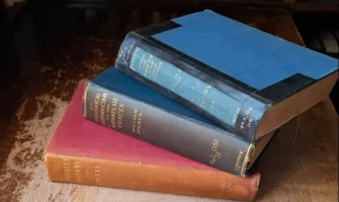 Three books piled on top of each other - one red, one blue, one black