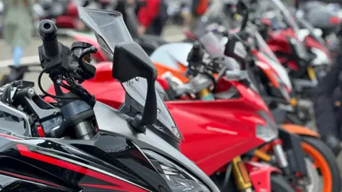 A close-up of a line of motorbikes, the front few are red.