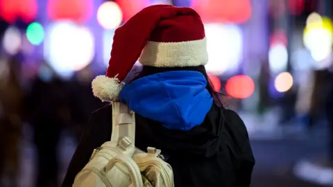 Getty Images Woman in Santa hat Christmas shopping