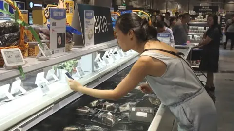 Alibaba Woman scanning product with smartphone