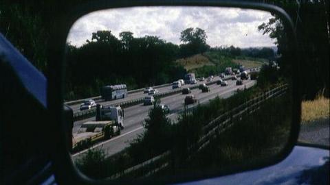 Car wingmirror shows a motorway with traffic on it