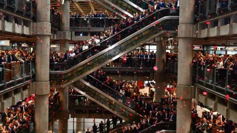 PA Poppies fall through the atrium of the Lloyd"s building during the Lloyd"s of London Armistice commemoration service.