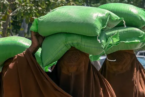 Abdul Majeed / AFP Women carry free bags of flour from a government distribution point in Peshawar, Pakistan, on 10 April 2023