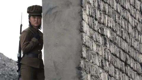 Getty Images A North Korea woman soldier patrols the bank of the Yalu River which separates the North Korean town of Sinuiju from the Chinese border town of Dandong