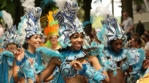 A group of female carnival dancers in blue and silver glittery outfits with scales and fins.