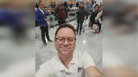 BBC Steve takes a selfie of himself in Paris at a baggage carousel in an airport