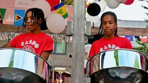 Bilal and his twin brother play the tenor pan at Notting Hill Carnival wearing red t-shirts that say RASPO. 
