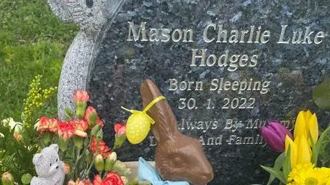 Supplied A gravestone commemorating mason's life.  There are flowers and a chocolate bunny near the grave. 