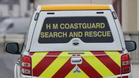 Getty Images The back of a HM Coastguard search and rescue vehicle. It is a white 4x4 and has yellow and red emergency markings on.