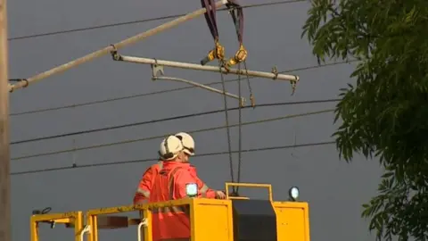 Engineers fixing overhead rail cables