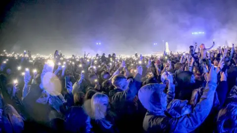 Getty Images The crowd at Leeds Festival 2024 during a night-time set by Fred Again, lit by blue light from the stage lights and by hundreds of mobile phone torchlights