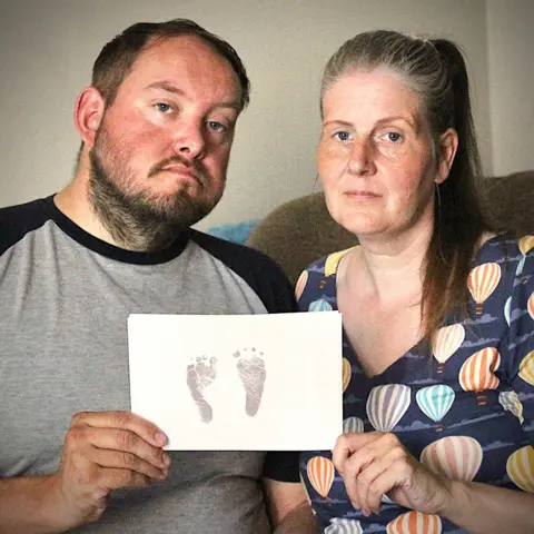 Supplied Sarah and Gary Andrews hold up their daughter's footprints.