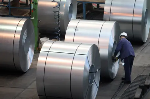 Getty Images A worker inspects steel in a factory