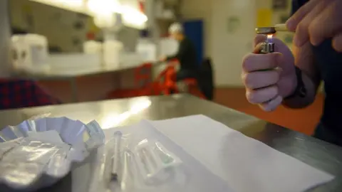 Getty Images Hands using a lighter to heat a spoon