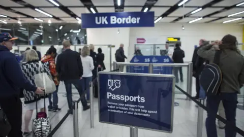 Getty Images Border Force check the passports of passengers arriving at Gatwick Airport