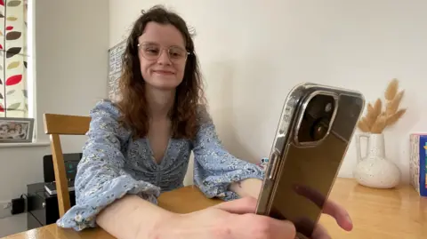 Shaun Whitmore/BBC Zoe Cawley holding an iphone