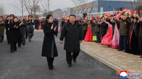 North Korean leader Kim Jong Un and his daughter, Kim Ju Ae, walking while crowd applauds on the side