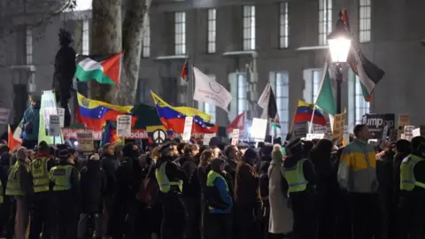 Reuters Police officers stand guard as demonstrators hold placards and flags during a London protest against US strikes against Venezuela and the seizure by US troops of Venezuelan President Nicolas Maduro.
