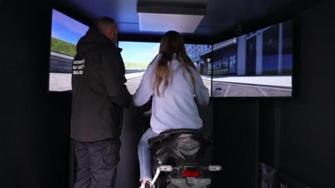 Girl trying out simulator of a motorbike crash