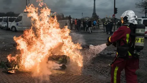 Getty Images Firefighters extinguish a fire lit on the street by ambulance drivers on Place de la Concorde during a national ambulance drivers" protest, in Paris, France, 03 December 2018