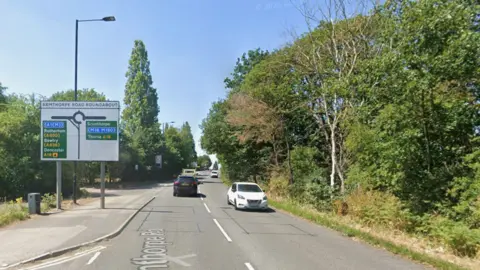 A road with a roundabout and road sign on the approach