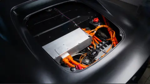 Нёболт. Внутри спортивного автомобиля — множество проводов и кабелей, аккуратно организованных вокруг большого металлического прямоугольника.