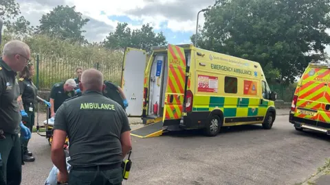 An ambulance crew and community first responders taking a patient to an ambulance
